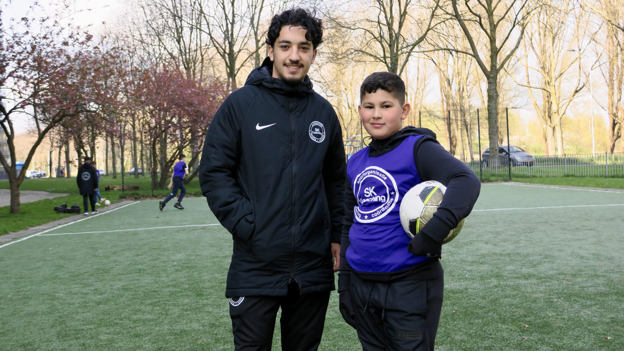 man en kind met voetbal in zijn hand op voetbalveld