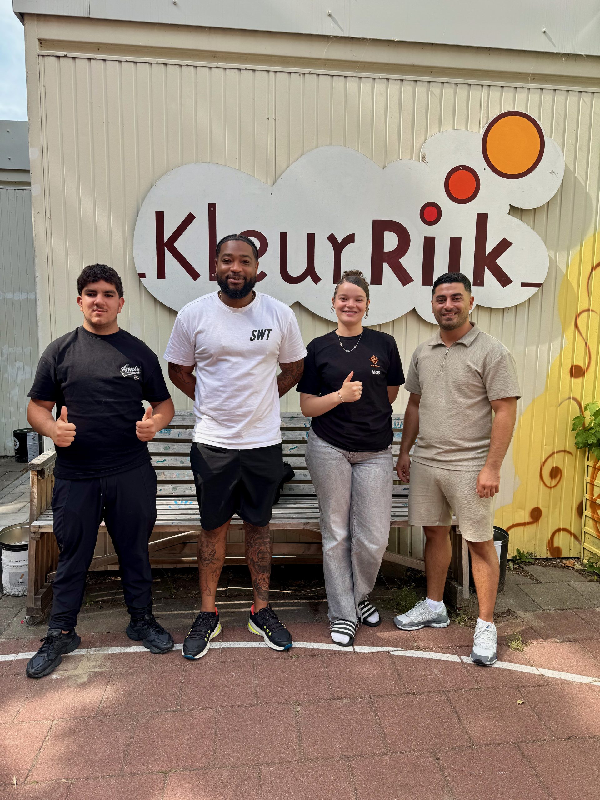 Vier jongeren op een rij buiten bij het buurtcentrum