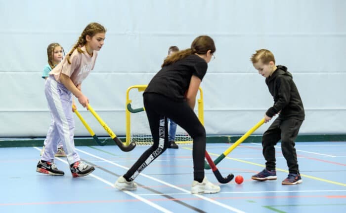 Een groepje kinderen is aan het indoor hockeyen.