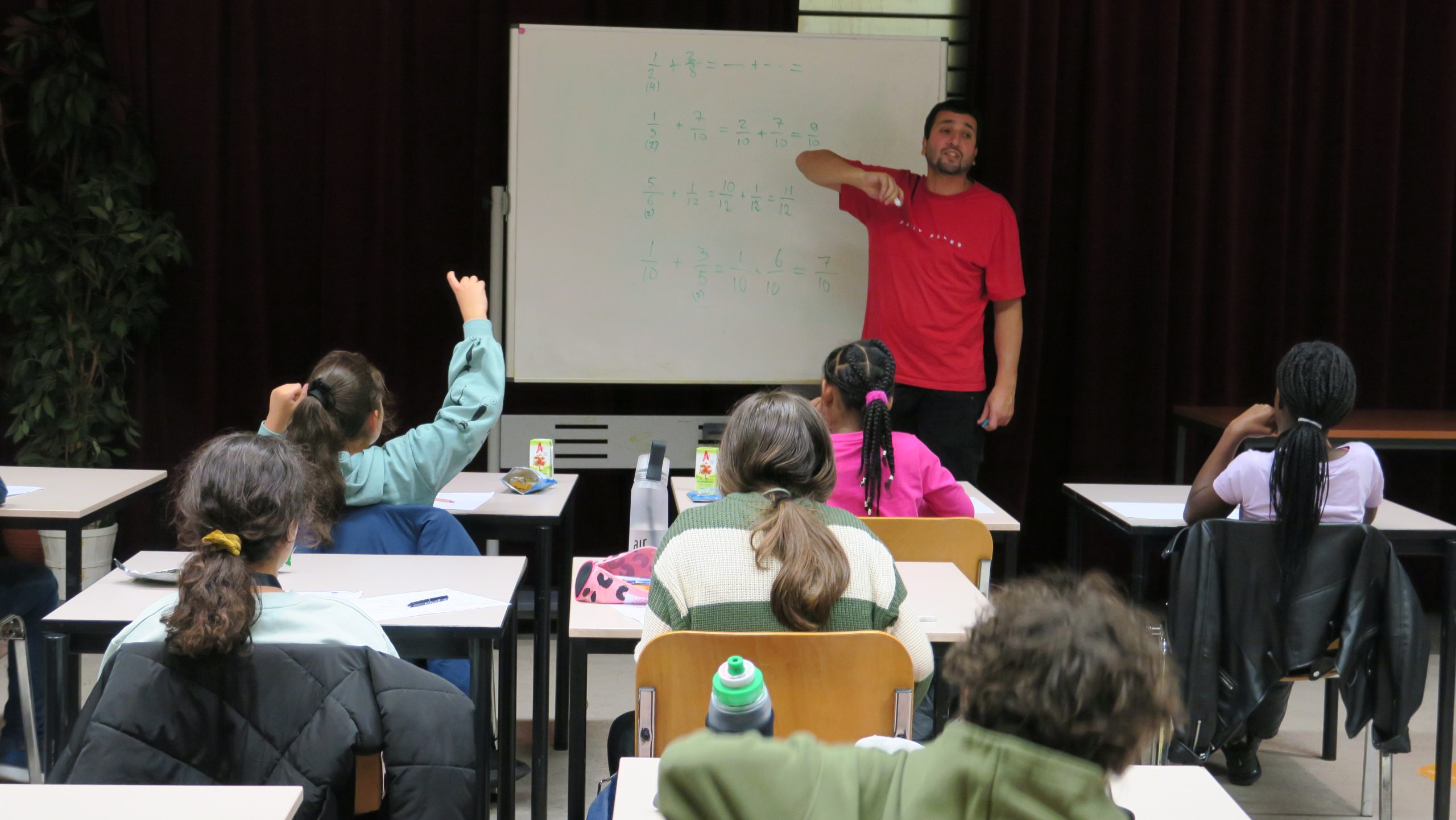 meester geeft kinderen bij het bord uitleg