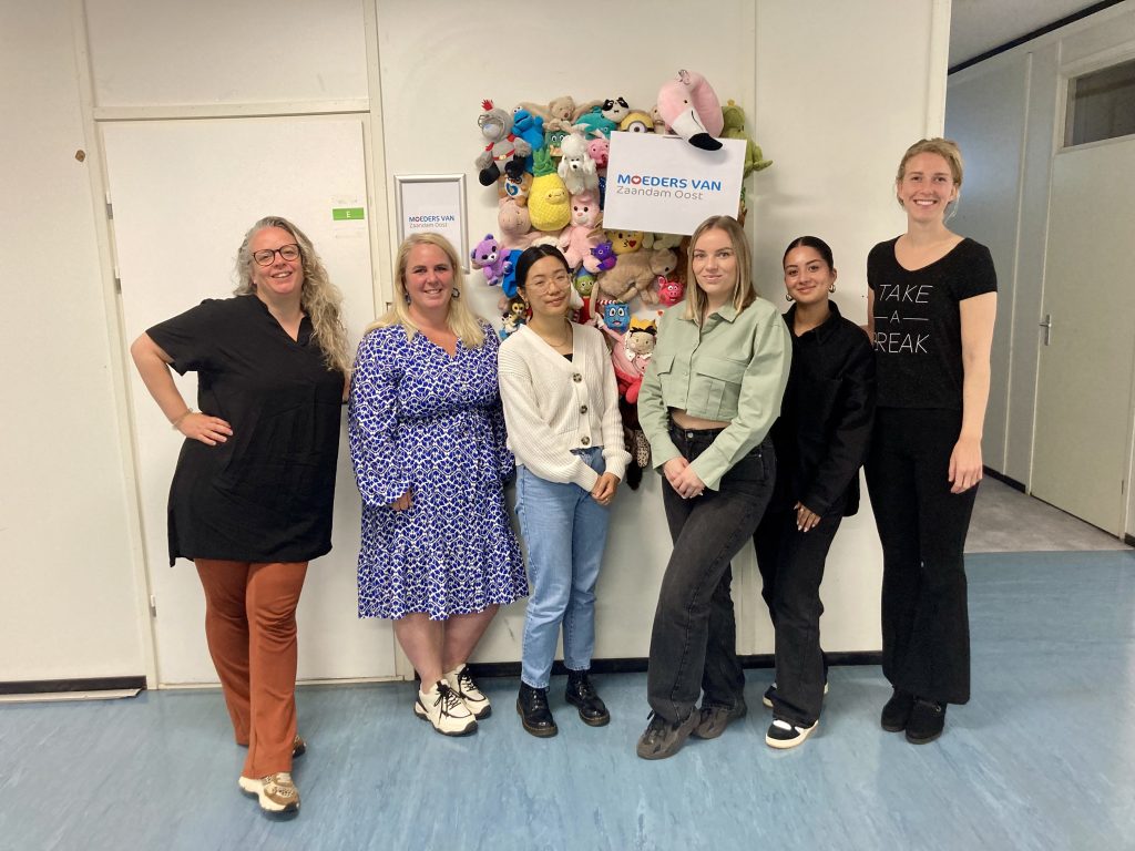 Groep vrouwen staan voor een muur met knuffels