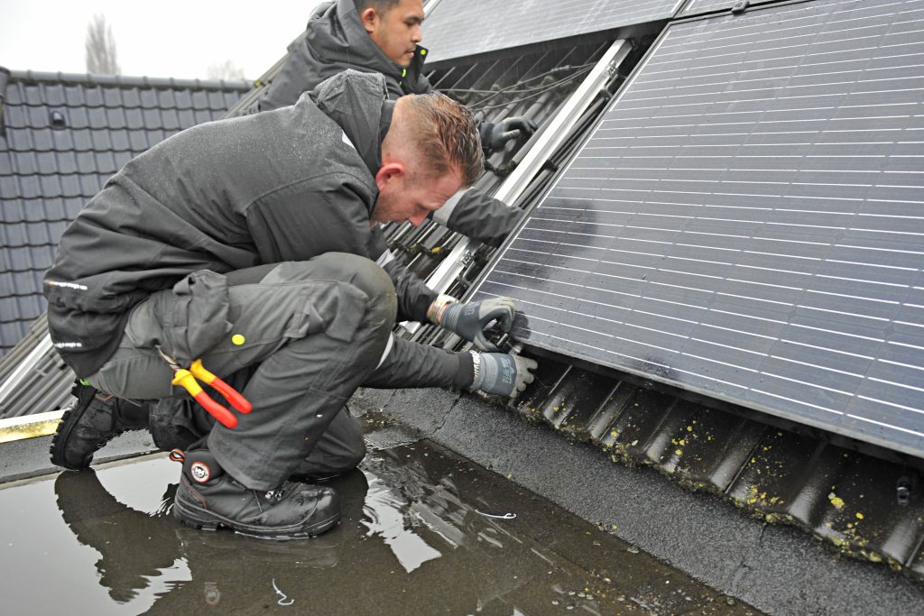 installateurs leggen zonnepanelen op een dak