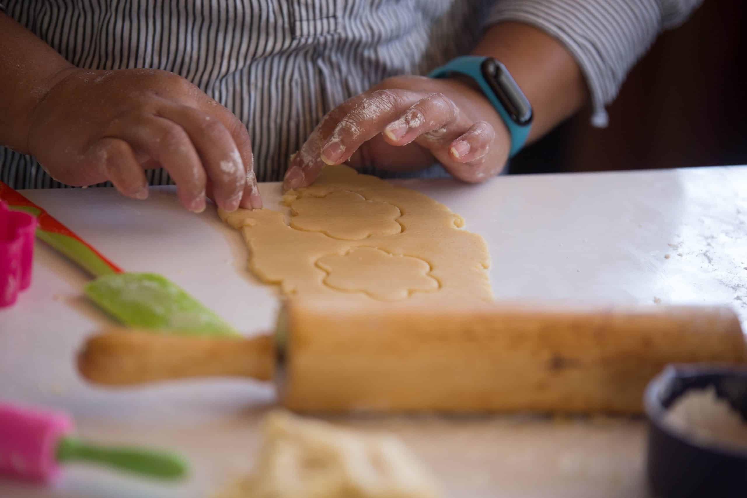 Kinderhandjes die een koekjesvorm in deeg heeft gestoken