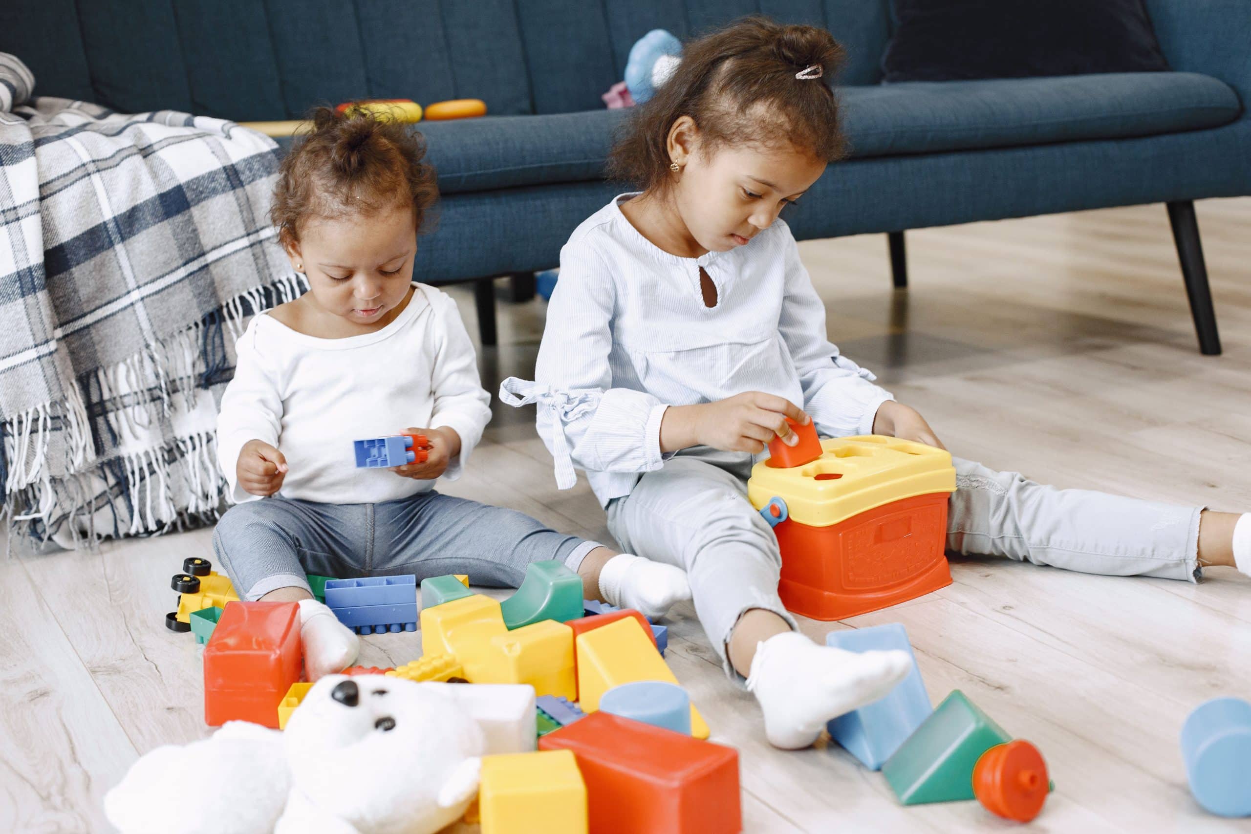 twee kinderen van één en drie jaar die met blokken spelen in een huiskamer